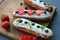 Delicious eclairs with strawberries and blueberries on a wooden cutting Board.