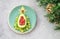 Delicious edible Christmas tree of avocado, frozen sweet raspberries and grapes on a blue plate on the table near the branches of