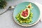 Delicious edible Christmas tree of avocado, frozen sweet raspberries and grapes on a blue plate on the table near the branches of