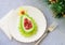 Delicious edible Christmas tree of avocado, frozen sweet raspberries and grapes on a blue plate on the table near the branches of