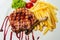 Delicious entrecote grilled steak on white plate with french fries and decorated with sauce.