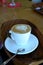 Delicious foamy cappuccino on a white cup on a plate