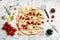 Delicious focaccia bread with olives and tomatoes on white marble table, flat lay