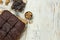 Delicious freshly baked brownies, walnuts and pieces of chocolate on white wooden table, flat lay. Space for text