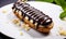 Delicious Freshly Baked Eclair with Smooth Shiny Chocolate Glaze Drizzled Over the Top Isolated on a White Background