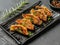 Delicious fried gyoza dumplings on a black rectangular plate. view from above