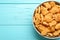 Delicious goldfish crackers in bowl on light blue wooden table, top view. Space for text