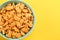 Delicious goldfish crackers in bowl on yellow background. Space for text