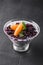 Delicious granola with yogurt, fresh berries, fruits in glass on black background.