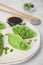 Delicious green dumplings (gyozas) and soy sauce on white tiled table, closeup