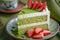 Delicious green tea cake garnished with fresh strawberries on a decorative plate