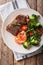 Delicious grilled beef steak with prawns and broccoli, tomatoes, arugula closeup on a plate. Surf and Turf. Vertical top view