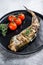 Delicious grilled hake with fresh thyme and tomatoes. Black background. Top view