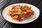 Delicious grilled pork chop with bell peppers, onions and basil close-up in a plate. horizontal