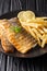 Delicious grilled sea bass filet served with french fries close-up on a plate. vertical