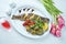 Delicious grilled seabass with lemon and a side dish of grilled vegetables mushrooms, tomatoes, bell peppers on a white plate.