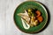delicious hake fillet with vegetables and sauce served on green plate