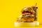 Delicious hamburger with cola and potato fries on a yellow background