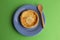 Delicious homemade cheese pie on a plate with a wooden spoon on a green background