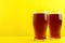 Delicious homemade kvass in glasses on yellow background.