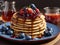 Delicious homemade pancakes with strawberries, blueberries and syrup on plate