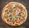 Delicious homemade pizza with tomatoes, sausage, onion, chicken and cheese wooden rustic background top view close up