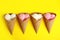 Delicious ice creams in wafer cones on yellow background