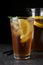 Delicious iced tea on grey table against black background  closeup