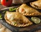 Delicious Indian samosa pastry presented on a plate with tomatoes and lettuce on a wooden table.