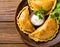 Delicious Indian samosa pastry presented on a plate with tomatoes and lettuce on a wooden table.