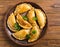 Delicious Indian samosa pastry presented on a plate with tomatoes and lettuce on a wooden table.