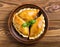 Delicious Indian samosa pastry presented on a plate with tomatoes and lettuce on a wooden table.