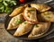 Delicious Indian samosa pastry presented on a plate with tomatoes and lettuce on a wooden table.