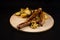 Delicious Italian sausage cooked on the grill with browned diced potatoes placed on a wooden cutting board with drops of mustard w