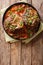 Delicious Italian veal steak Ossobuco alla Milanese with gremolata and vegetable sauce close-up. Vertical top view