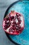 Delicious, juicy half cut pomegranate on a blue handmade ceramics plate