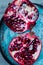 Delicious, juicy half cut pomegranate on a blue handmade ceramics plate