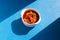 Delicious juicy stewed vegetables in a spicy tomato sauce in a white bowl, top view. Sunlight and harsh shadows. Blue background