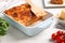 Delicious lasagna in baking dish on white table