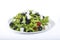 Delicious leafy vegetable salad on a white plate with black olives and fresh tofu