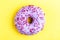 Delicious lilac donut with sprinkle on bright yellow background