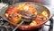 delicious looking baked dish of stuffed tomatoes and Capsicum with potatoes in a steel red hot Pan