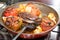 delicious looking baked dish of stuffed tomatoes and Capsicum with potatoes in a steel red hot Pan