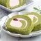 Delicious Matcha Swiss Roll Cake slices with strawberry cream on white background