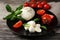 Delicious mozzarella with tomatoes and basil leaves on wooden table, closeup