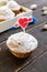 Delicious muffin with powdered sugar and a heart-shaped candle on a wooden table. Festive cakes.