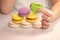 Delicious multi-colored cookies in the hands of a child. Macaron. Kid girl bites pistachio green macaron cookie. Dessert