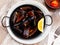 Delicious mussels on a frying pan with lemon at table