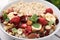 Delicious oatmeal with freeze dried berries, banana, nuts and mint in bowl, closeup