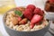 Delicious oatmeal with freeze dried strawberries, almonds and mint in bowl, closeup